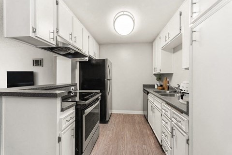 A kitchen with black appliances and white cabinets.