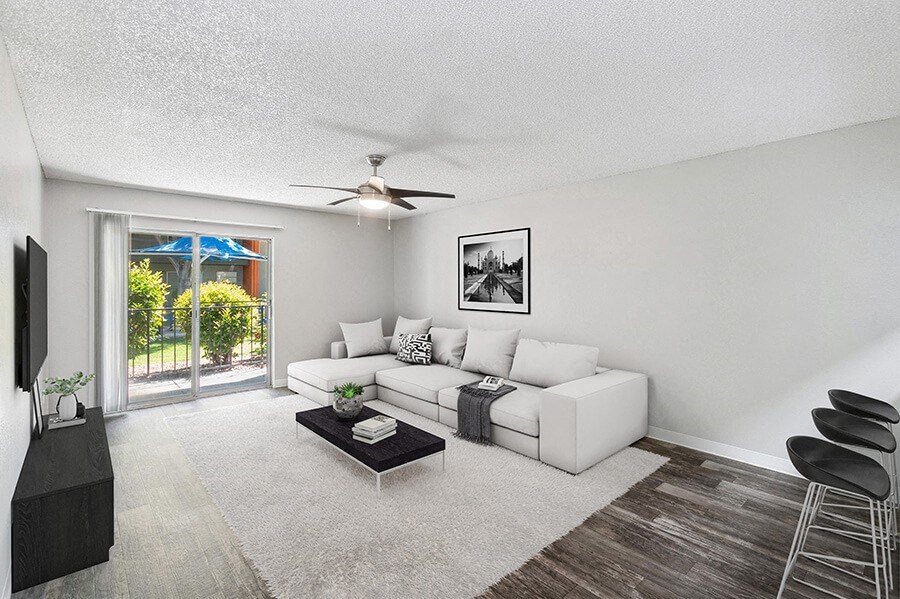 Model Living Room with Wood-Style Flooring and Patio Accessibility at Indigo Park Apartments located in Albuquerque, NM.