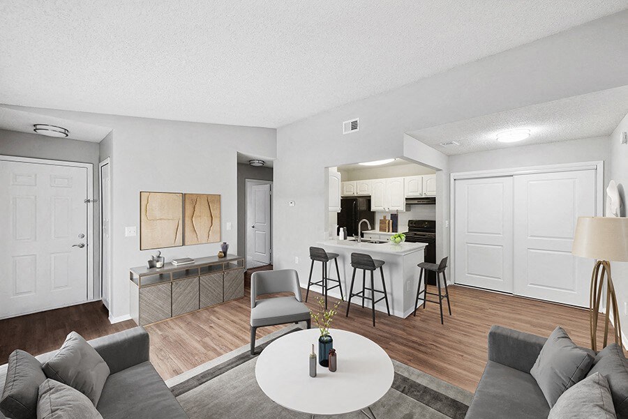 Model Living Room with Wood-Style Flooring and View of Kitchen at Vue at Baymeadows Apartments in Jacksonville, FL.