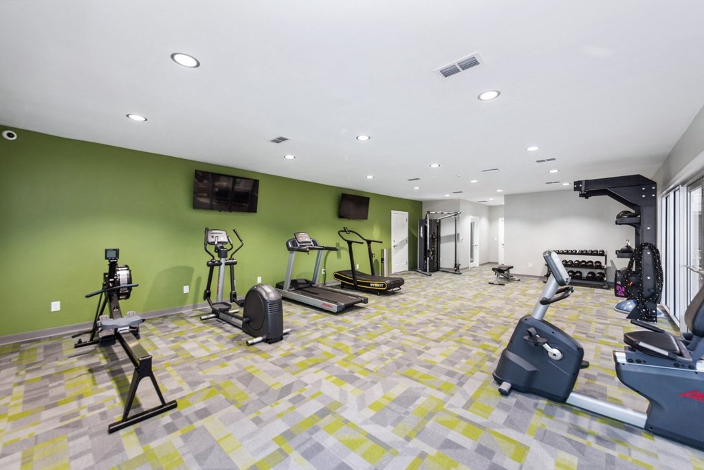 a gym with weights and cardio equipment in a building with green walls