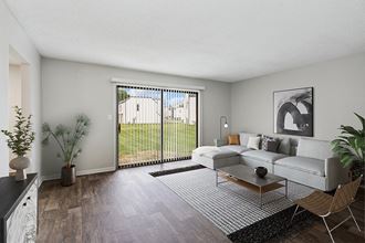 Model Living Room with Wood-Style Flooring and Patio Accessibility at Parc at Creekside Apartments in Kansas City, MO.