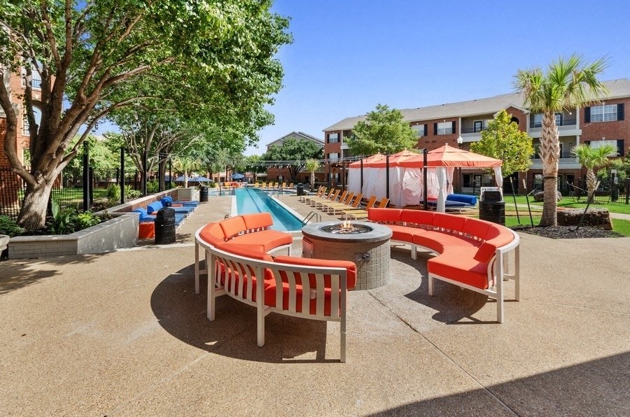 Gas fire-pit surrounded by patio couches and trees