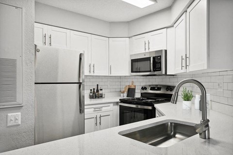 a white kitchen with a sink and a refrigerator