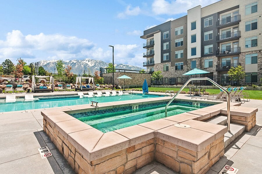 Community Hot Tub and Swimming Pool with Pool Furniture at Seven Skies Apartments located in Sandy, UT.