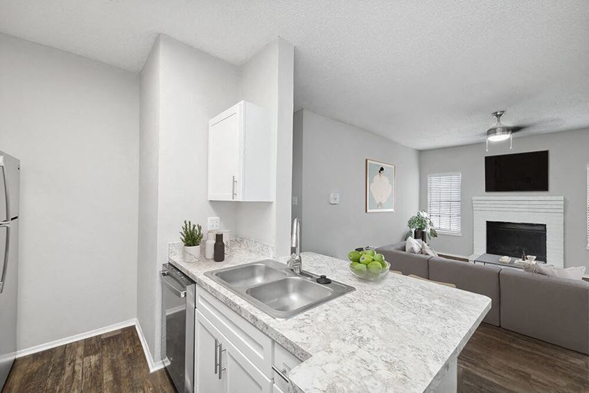 Model Kitchen with White Cabinets and Wood-Style Flooring at Heatherstone Apartments in Dallas, TX.
