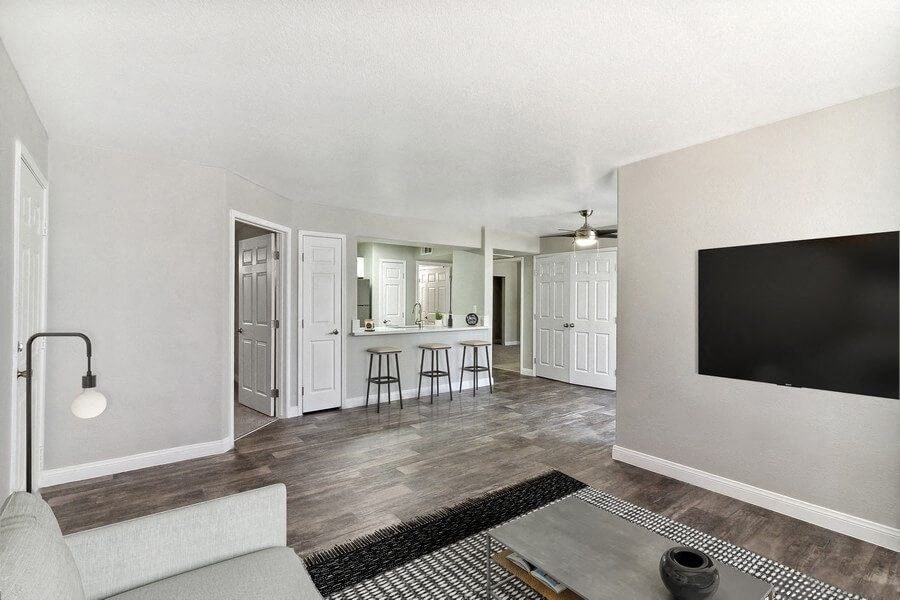 Model living room with a television and a kitchen in the background