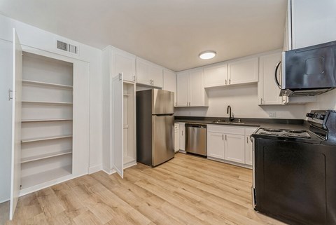 A kitchen with white cabinets and a black fridge.