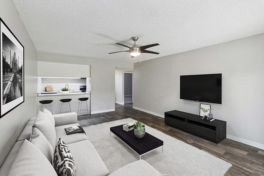 Model Living Room with Wood-Style Flooring and View of Kitchen at Indigo Park Apartments located in Albuquerque, NM.