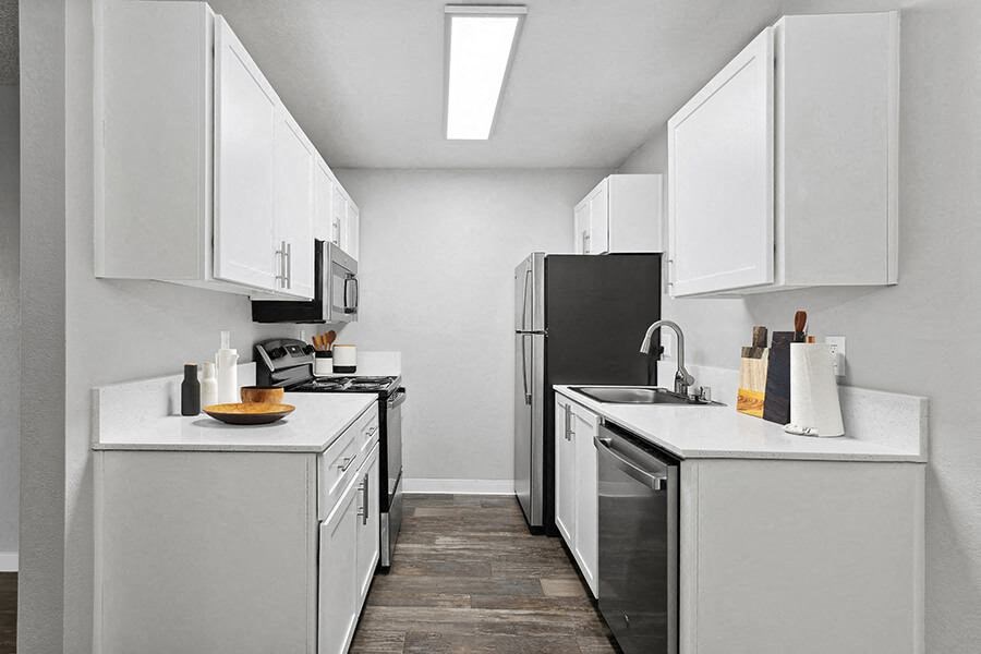 Model Kitchen with White Cabinets and Wood-Style Flooring at The Archer Apartments in Sacramento, CA.