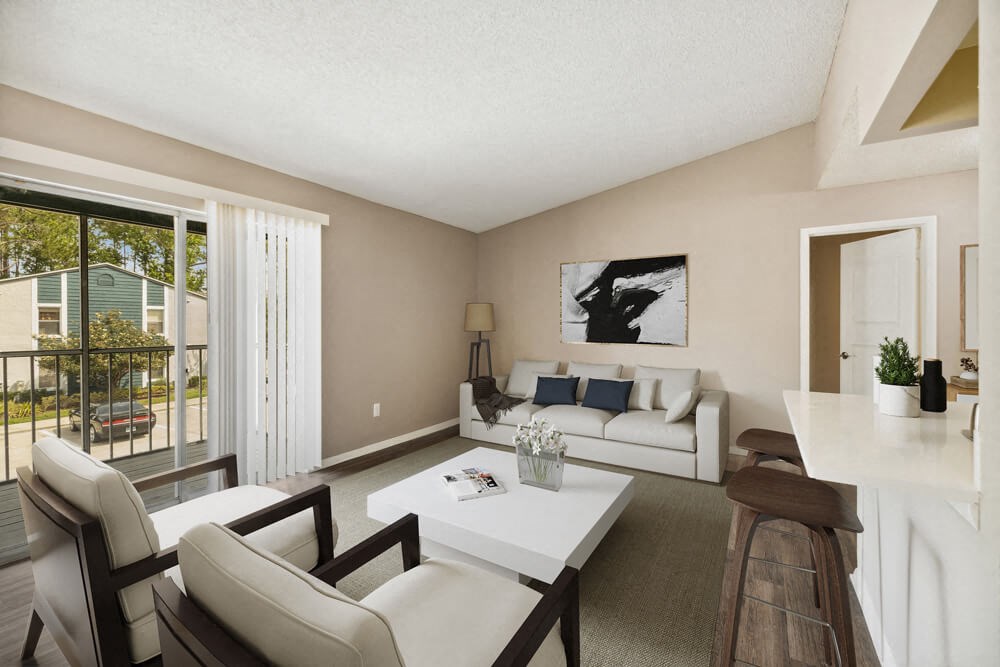Living room with a white couch and a white coffee table in front of a sliding glass at Vue at Baymeadows Apartments in Jacksonville, Florida