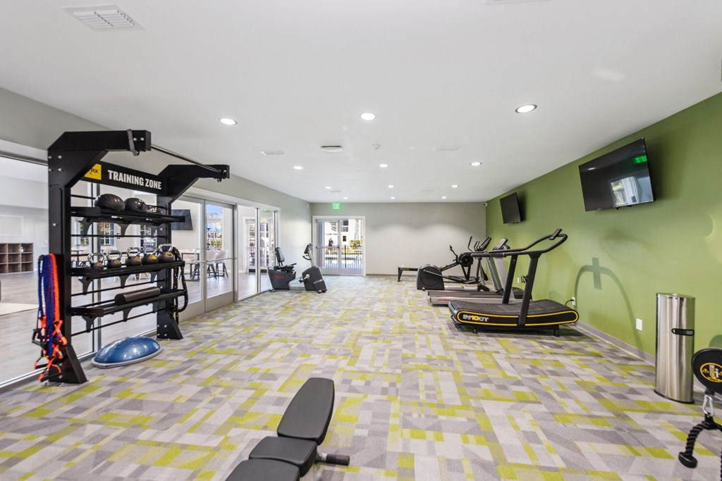 a workout room with weights and cardio equipment and a wall mounted tv