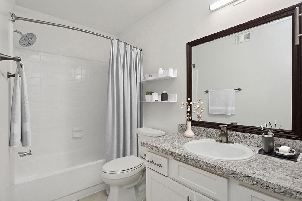 Model Bathroom with White Cabinets and Tile Flooring at Carrollwood Station Apartments in Tampa, FL.