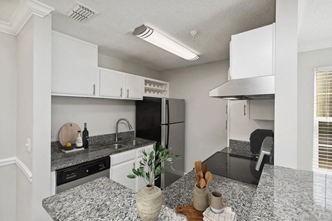 a kitchen with granite counter tops and a stainless steel refrigerator
