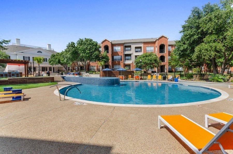 Large round swimming pool in middle of landscape and apartment buildings