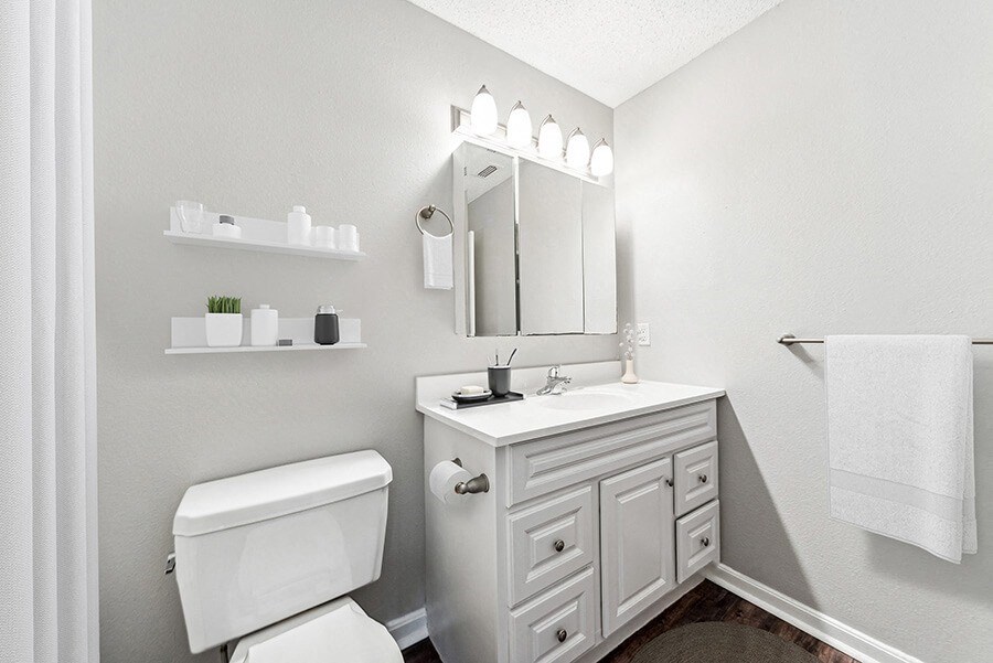 Model Bathroom with White Cabinets and Wood-Style Flooring at Commons at Haynes Farm Apartments in Shrewsbury, MA.