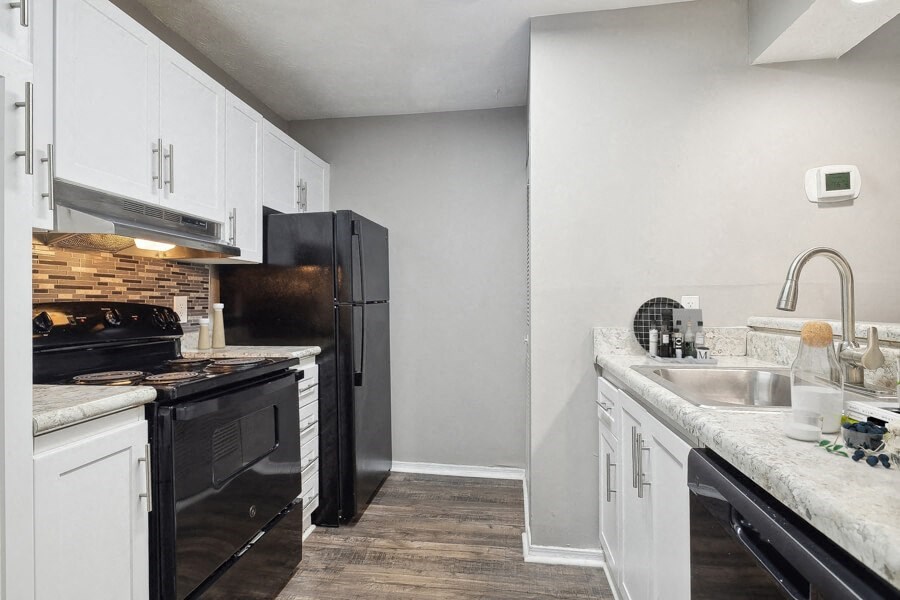 Model apartment kitchen with black appliances and white cabinets