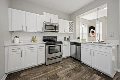 a white kitchen with stainless steel appliances and white cabinets
