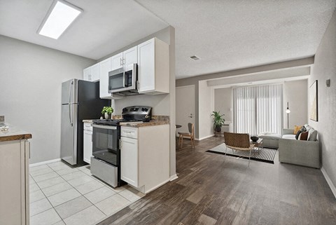 a kitchen and living room with a refrigerator and microwave