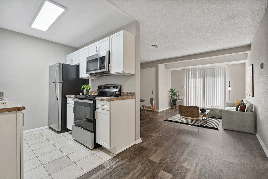 Model Kitchen with White Cabinets and Tile Flooring with View of Living Room with Wood-Style Flooring Model Kitchen with White Cabinets and Tile Flooring with View of Living Room with Wood-Style Flooring at Liberty Creek Apartments in Aurora, CO.