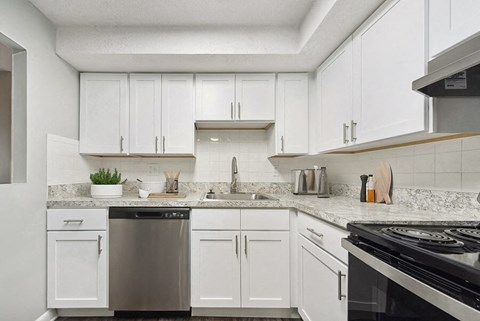 a white kitchen with white cabinets and a black stove