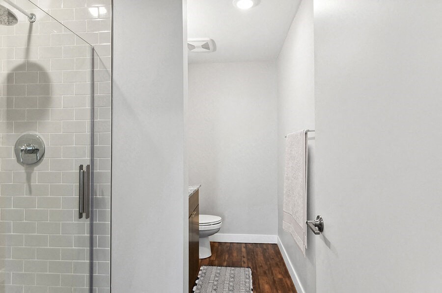Model Bathroom with Wood-Style Flooring, Dark Oak Cabinets & Shower/Tub at Seven Skies Apartments located in Sandy, UT.