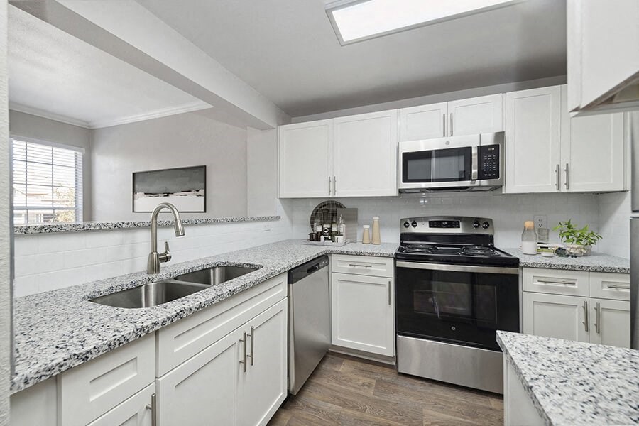 Model Kitchen with White Cabinets and Wood-Style Flooring at Chapel Hill Apartments in Lewisville, TX.