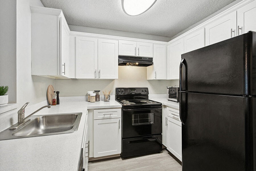 Model Kitchen with White Cabinets and Wood-Style Flooring at Huntington Place Apartments located in Sarasota, FL.