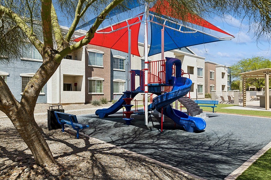 Community Playground with Slide and Blue/Red Canopy at Ridgeline Apartments in Tucson, AZ.
