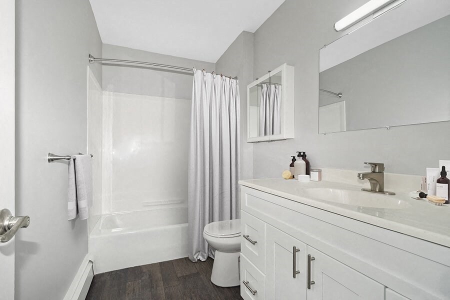 Model Bathroom with White Cabinets and Wood-Style Flooring at Stone Ends Apartments in Stoughton, MA.