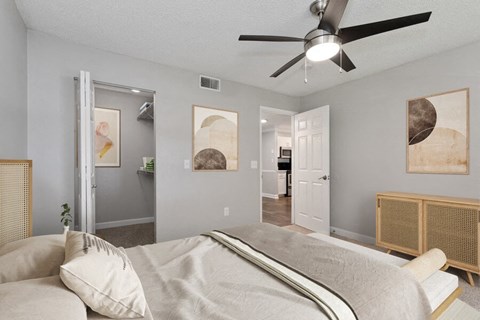 North St. Petersburg, FL, Apartments with In-Unit Washer and Dryer - Bridges at Bayside - A Bedroom With A Bed, Framed Art, A Ceiling Fan With Light, And A Spacious Closet.
