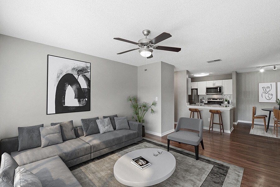 Model Living Room with Wood-Style Flooring and View of Kitchen/Dining Area at Fountains Lee Vista Apartments in Orlando, FL.