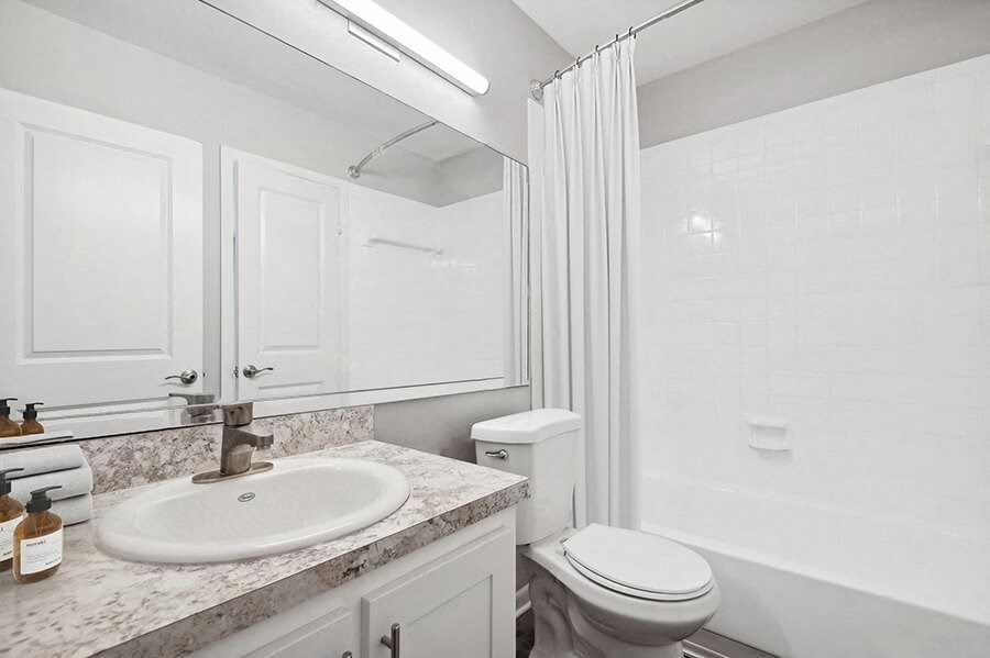 Model Bathroom with Wood-Style Flooring, White Cabinets & Shower/Tub at Rosehill Preserve Apartments located in Orlando, FL.