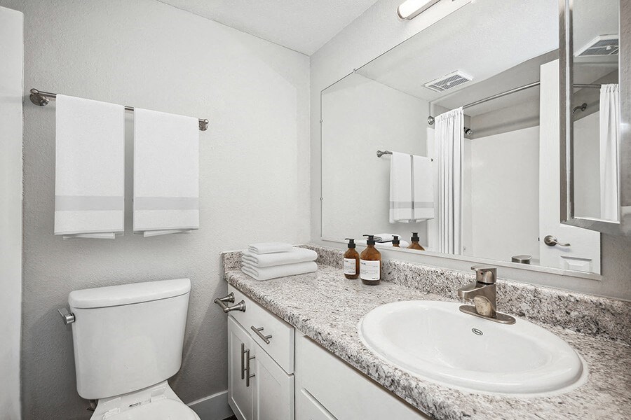 Model Bathroom with White Cabinets and Wood-Style Flooring at Stillwater Apartments located in Glendale, AZ.