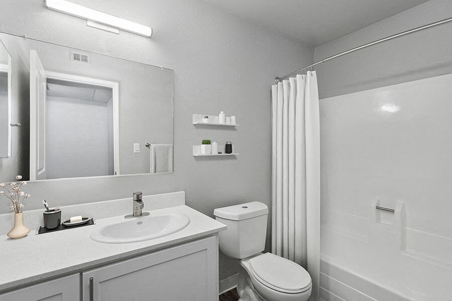 Model Bathroom with White Cabinets and Wood-Style Flooring at The Archer Apartments in Sacramento, CA.