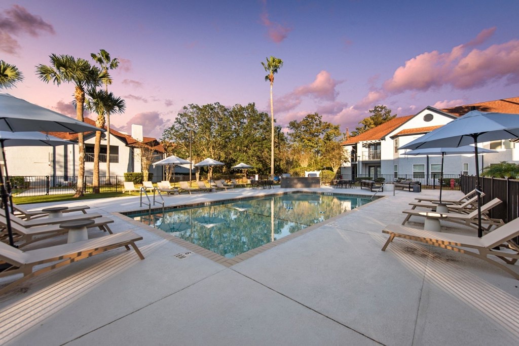 a swimming pool with lounge chairs and umbrellas at the resort with a building