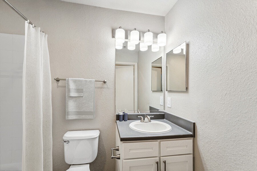 Model Bathroom with White Cabinets, Wood-Style Flooring & Shower/Tub at Lake Cameron Apartments located in Apex, NC.