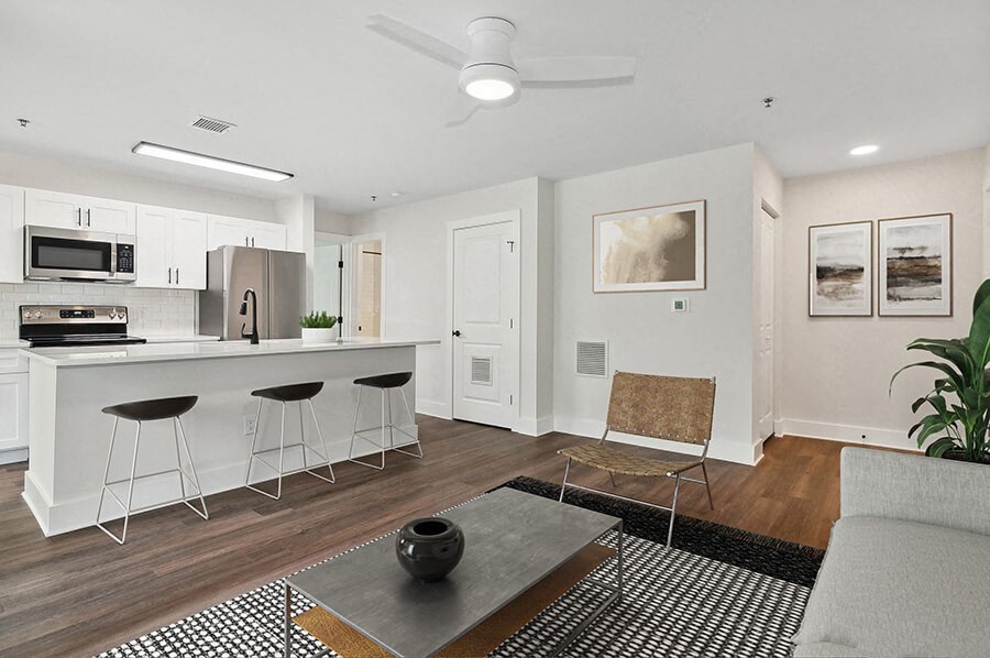 Model Living Room with Wood-Style Flooring and View of Kitchen at Park at Caterina Apartments located in Charlotte, NC.