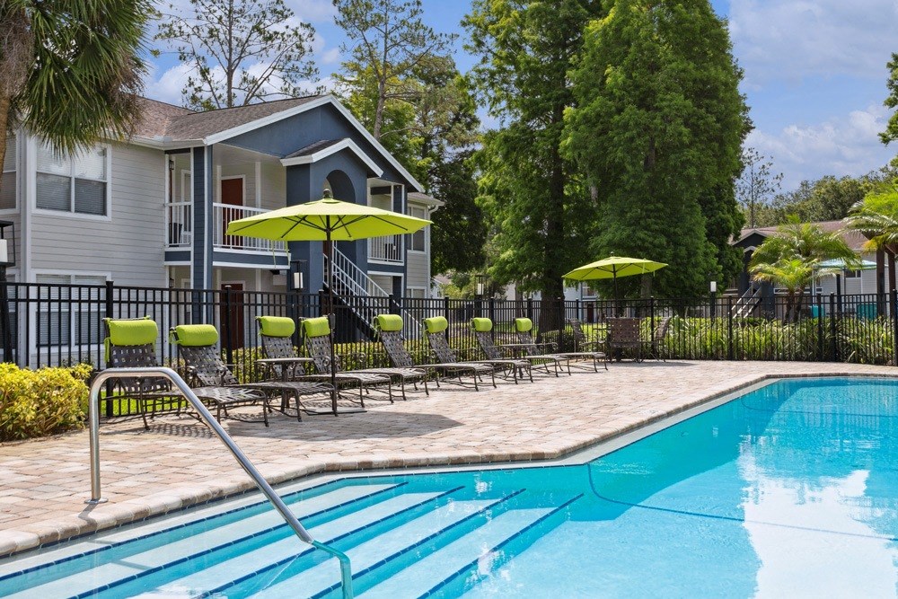 Swimming pool with chaise lounge chairs and umbrellas in front of a house