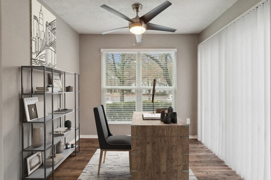 Model apartment room with a desk, large window and a ceiling fan