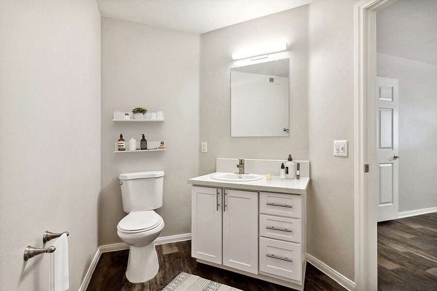 Model Bathroom with Wood-Style Flooring and White Cabinets at Loma Vista Apartments in Las Vegas, NV.