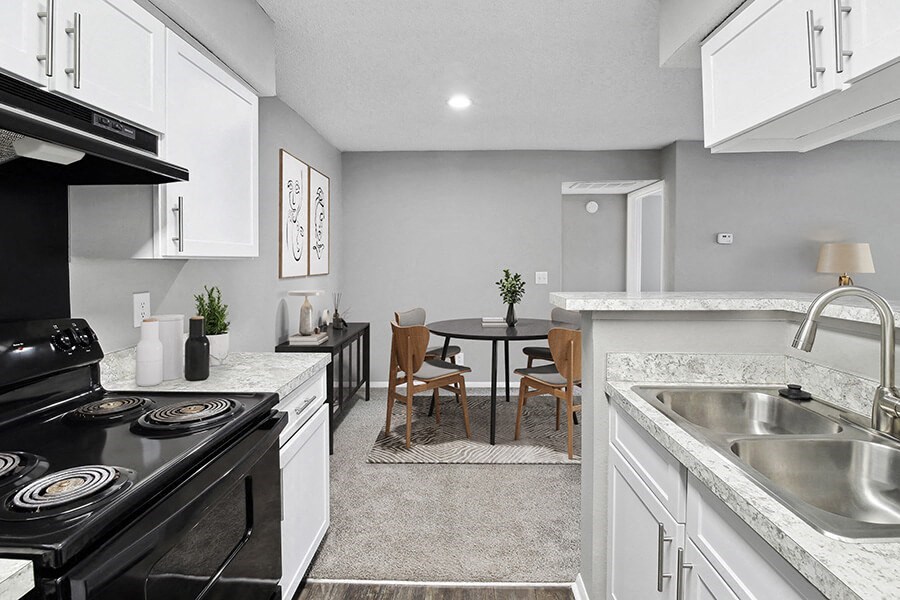 Model Kitchen with White Cabinets, Wood-Style Flooring and View of Dining Room at Abbington Heights Apartments in Antioch, TN.