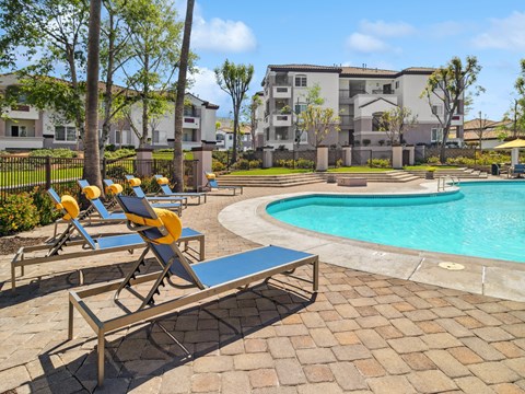 A poolside area with sun loungers and a bench.
