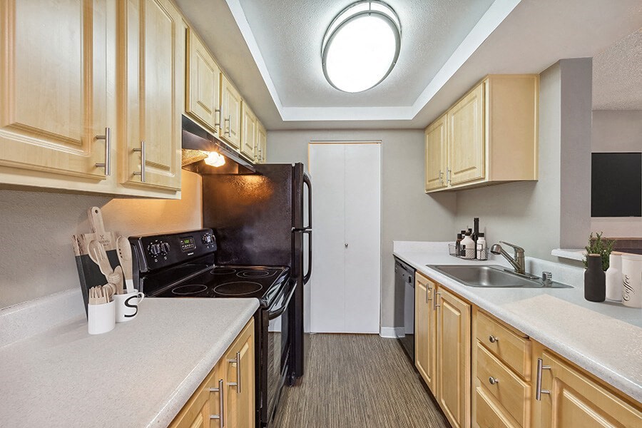 Model Kitchen with Dark Wood Cabinets and Wood-Style Flooring at Grammercy Apartments located in Renton, WA.