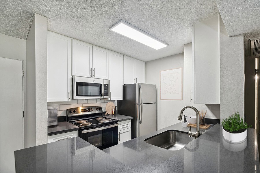Model Kitchen with White Cabinets and Wood-Style Flooring at Madison Park Apartments located in Anaheim, CA.