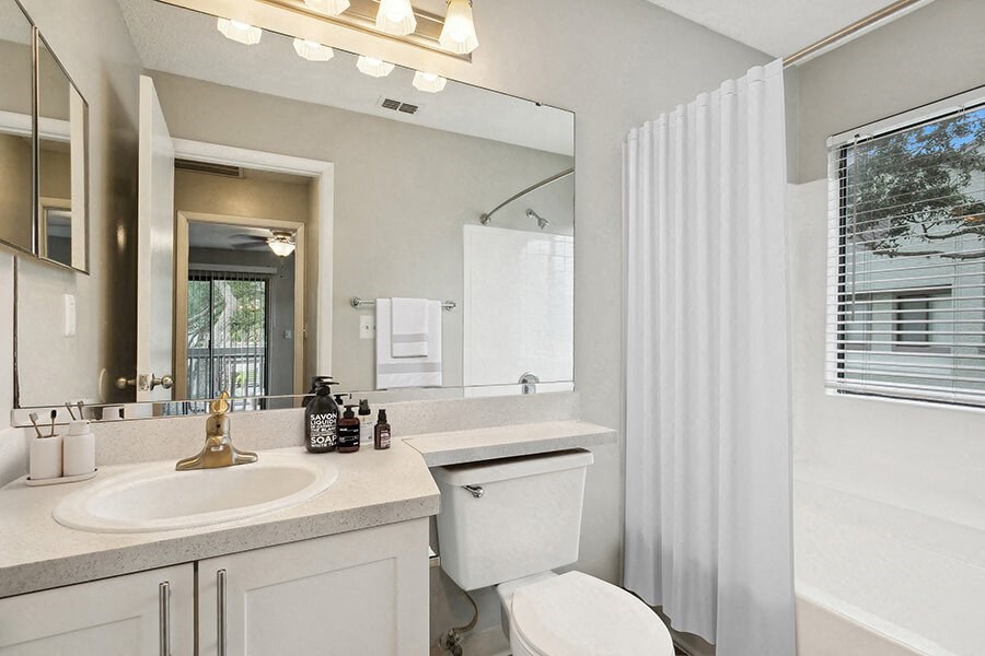 Model Bathroom with White Cabinets, Wood-Style Flooring & Shower/Tub at Huntington Place Apartments located in Sarasota, FL.