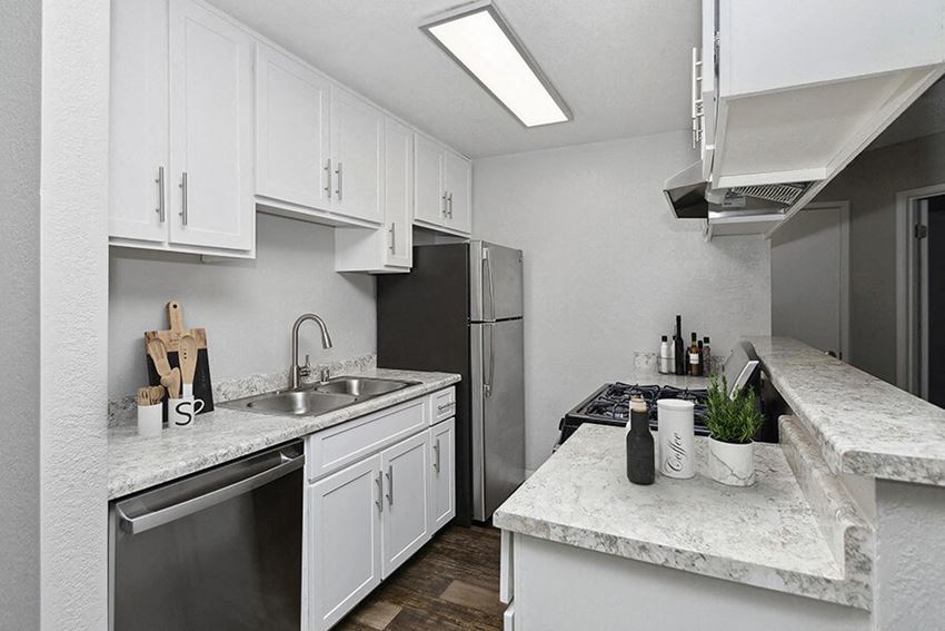 Model Kitchen with White Cabinets and Wood-Style Flooring at The Meritage Apartments in Vallejo, CA.