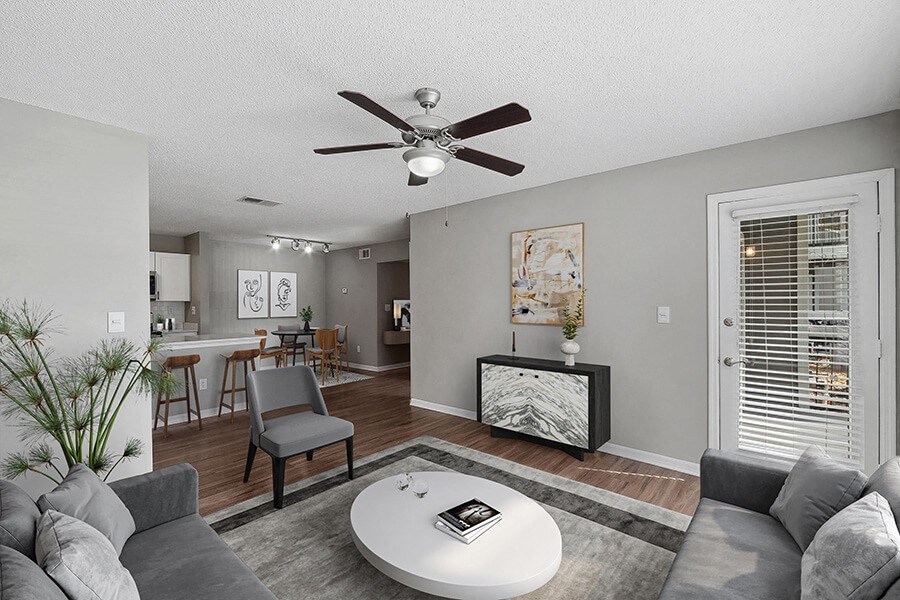 Model Living Room with Wood-Style Flooring and View of Kitchen/Dining Area at Fountains Lee Vista Apartments in Orlando, FL.