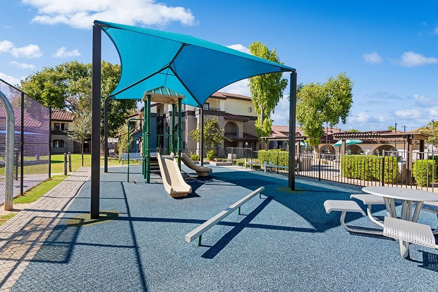 Community Playground with Slide and Blue Canopy at Stillwater Apartments in Glendale, AZ.