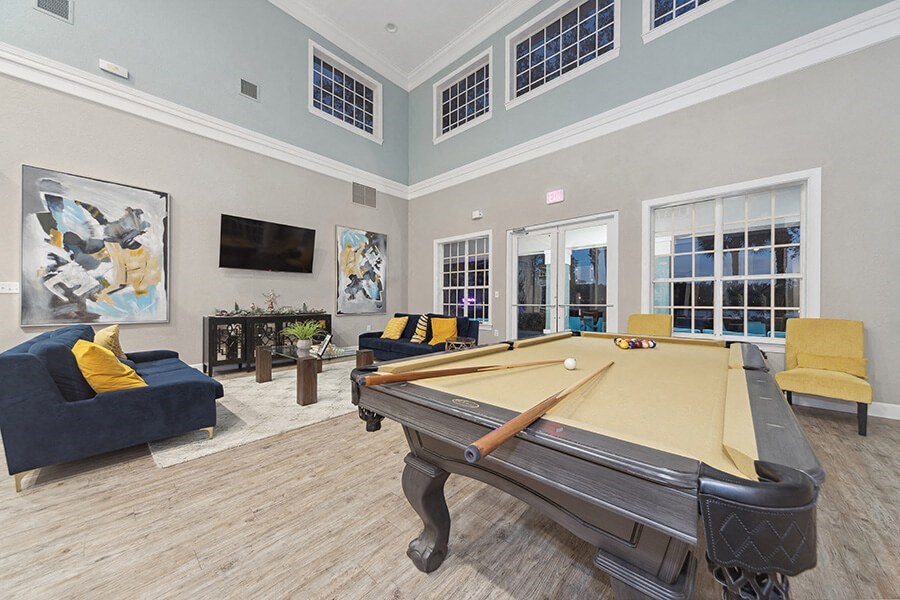 Community Clubhouse with Lounge Furniture and Pool Table Area at Vinings at Hunter's Green Apartments in Tampa, FL.
