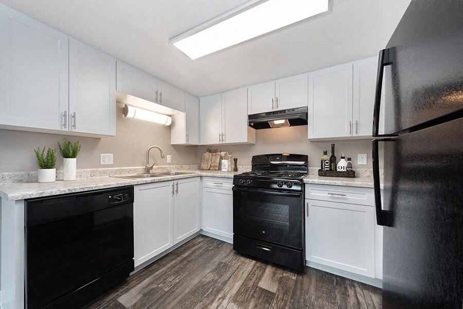 Model Kitchen with White Cabinets and Wood-Style Flooring at Bridges at 9 Mile Station Apartments in Denver, CO.